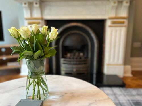a vase of flowers sitting on a table with a fireplace at 34 One in Lytham St Annes