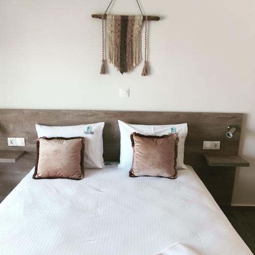 a bedroom with a large white bed with three pillows at elenamou rooms in Ammouliani