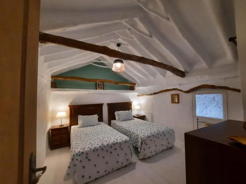 1 dormitorio con 2 camas y techo blanco en Casa Arroyo - Rosa & Nispero, en Iznájar