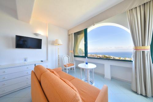 un soggiorno con divano arancione e una grande finestra di Paradiso Terme Resort & SPA con 5 piscine termali a Ischia