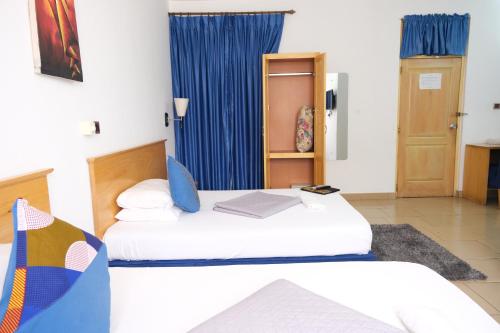 um quarto com 2 camas e uma cortina azul em Asantewaa Premier Hotel em Kumasi