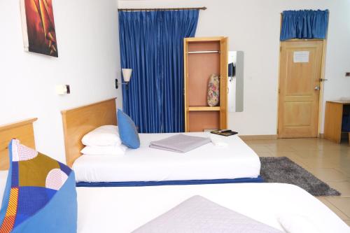 a bedroom with two beds and a blue curtain at Asantewaa Premier Hotel in Kumasi