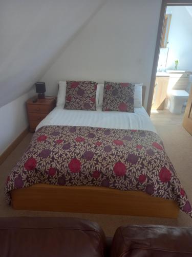a bedroom with a bed with a flowered bedspread at Shepherds Loft in Ullenhall
