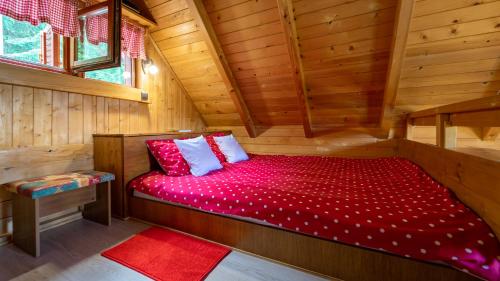 a bed in a log cabin with a red comforter at Chalet Woody in Stara Sušica