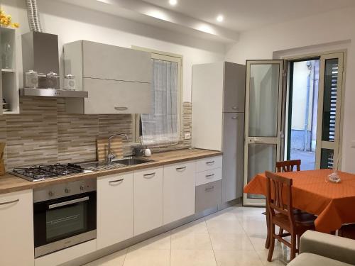 une cuisine avec des placards blancs, une table et une salle à manger dans l'établissement Da Cristina Con Amore, à Taormine