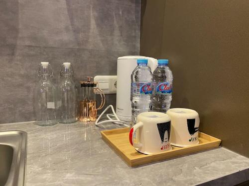 a counter top with two cups and bottles of water at Casanty at Benson Apartment in Lontar