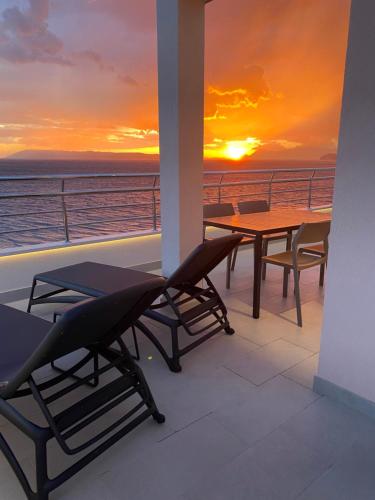a balcony with a table and chairs and a sunset at Luxury Penthouse Adriatic Blue - On the beach in Tučepi