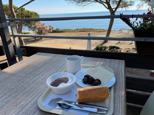 einen Teller mit Essen auf einem Tisch mit Blick auf den Strand in der Unterkunft Le Village des Isles in Taglio-Isolaccio