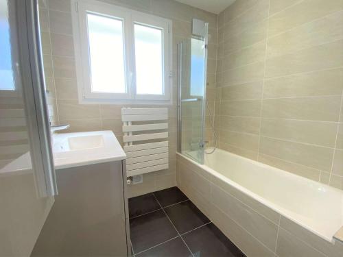 La salle de bains est pourvue d'un lavabo, d'une baignoire et d'une fenêtre. dans l'établissement Grande maison 4* à Beg Meil avec jardin, à 1 km de la plage - FR-1-481-119, à Fouesnant