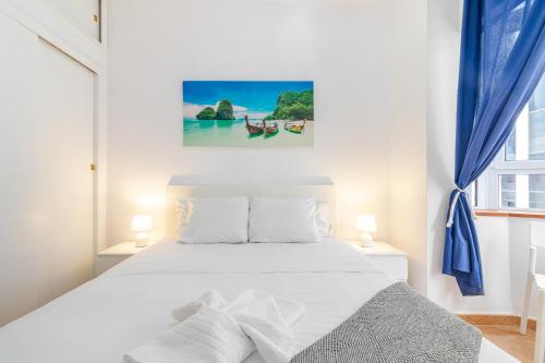 a bedroom with a white bed and a window at Lovely Flat Santa Catalina Park in Las Palmas de Gran Canaria