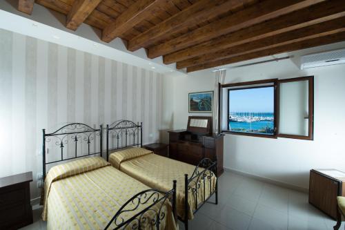 a bedroom with two beds and a desk and a window at Hotel Aliai in Sciacca
