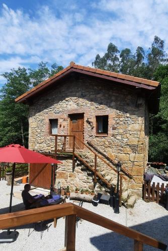 a man sitting in front of a stone building at Posada Pet Friendly El Molino de Cantabria in Entrambasaguas