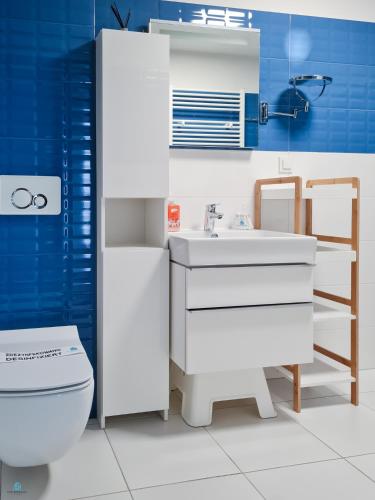 a bathroom with a white sink and a toilet at Pod Brzozami Apartamenty 5 Mórz in Ustronie Morskie