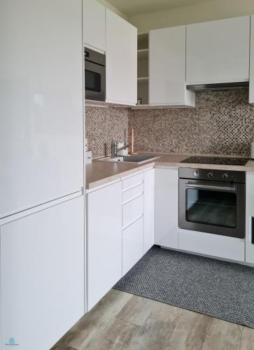 a white kitchen with white cabinets and a stove at Pod Brzozami Apartamenty 5 Mórz in Ustronie Morskie
