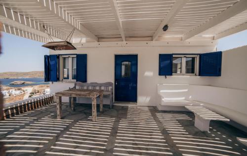 a porch with blue doors and a table and benches at Eternal Blue Kythnos in Mérikhas