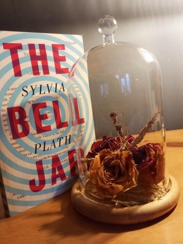 a glass dome with a rose in it next to a book at Hebble End View B&B in Hebden Bridge