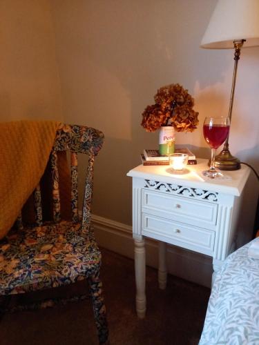 a bedroom with a table with a glass of wine and a chair at Hebble End View B&B in Hebden Bridge