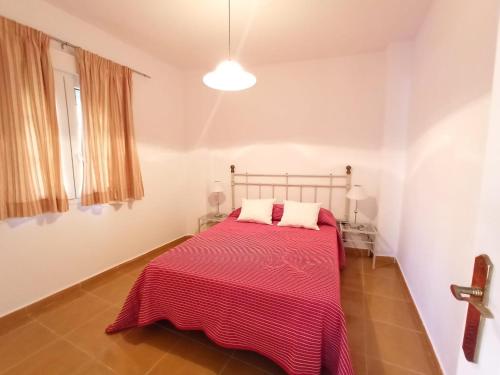 - une chambre avec un lit et une couverture rouge dans l'établissement Acogedor apartamento a 50 metros de la playa, à Isla Canela