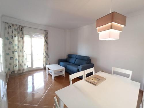 een woonkamer met een blauwe bank en een tafel bij Acogedor apartamento a 50 metros de la playa in Isla Canela