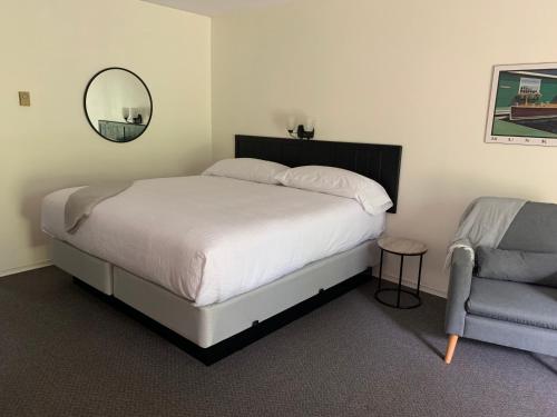 a bedroom with a bed and a chair and a mirror at Colonial Bay Motel and Cottages in Huntsville