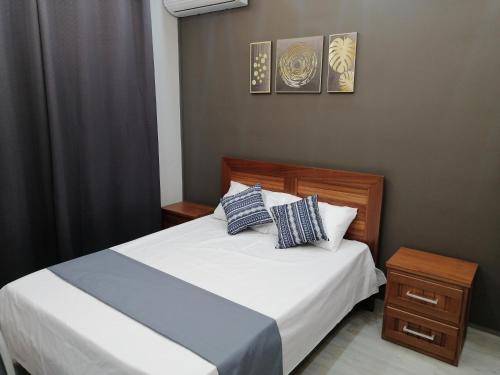 a bedroom with a bed with white sheets and blue pillows at VH Newave holiday in Flic-en-Flac