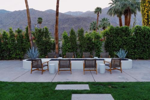 a patio with chairs and a table with mountains in the background at Azure Sky Hotel - Adults Only in Palm Springs