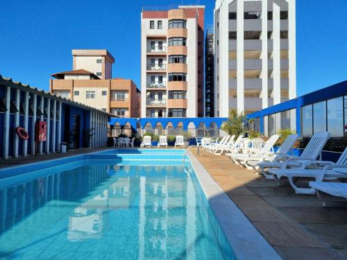 バルバセーナにあるLucape Palace Hotelの白いラウンジチェアと建物のあるスイミングプール