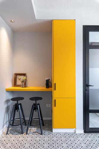 a yellow door in a room with two stools at Levinski Market Hotel in Tel Aviv