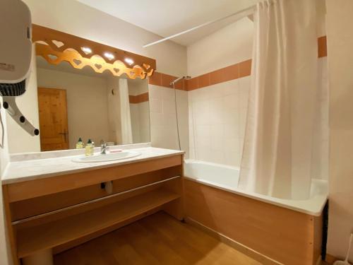 une salle de bain avec un lavabo, une baignoire et un miroir dans l'établissement Studio à Samoëns avec piscines, sport, parking et animaux acceptés - FR-1-624-108, à Samoëns