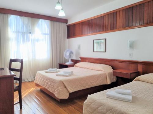a hotel room with two beds and a table and chair at Lucape Palace Hotel in Barbacena