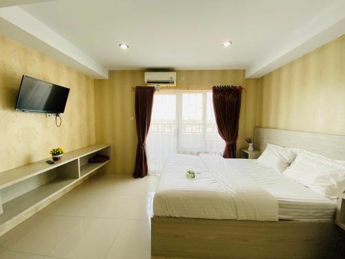 Hozby Skyview Setiabudi في Sunggal: غرفة نوم مع سرير وتلفزيون على الحائط