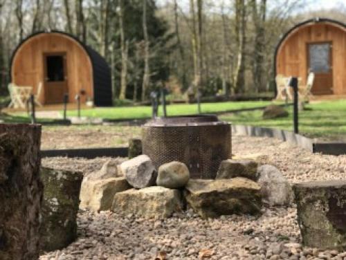 a park with rocks and a tree stump and a building at Wilding on a Whim in West Linton