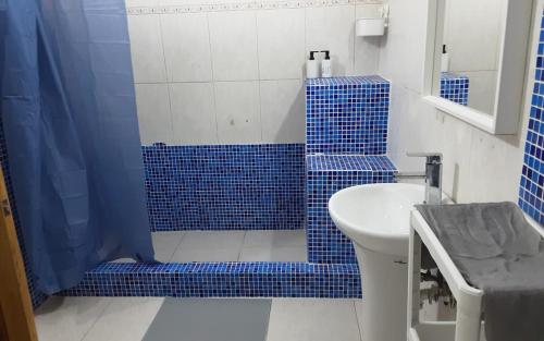 y baño con ducha de azulejos azules y lavamanos. en Villa Colonial suite n 3 familiar, en Río San Juan