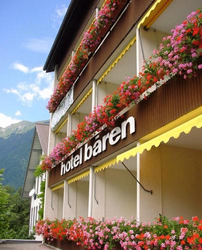 a hotel sign on the side of a building with flowers at Seehotel Bären in Brienz