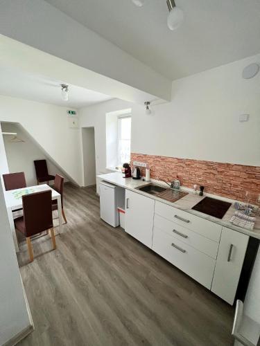 a kitchen with white cabinets and a brick wall at Penzion Rozárka in Přísečná
