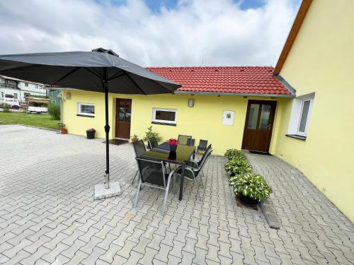 a patio with an umbrella and a table and chairs at Penzion Rozárka in Přísečná
