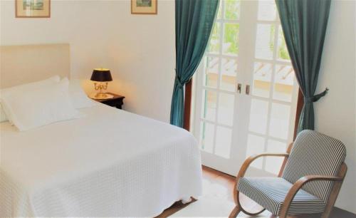 a bedroom with a bed and a chair and a window at Maison de Campagne, Chambres D'Hôtes - Itaipava in Itaipava