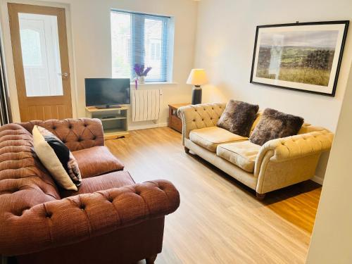 a living room with two couches and a television at Grassington Cottage in Grassington