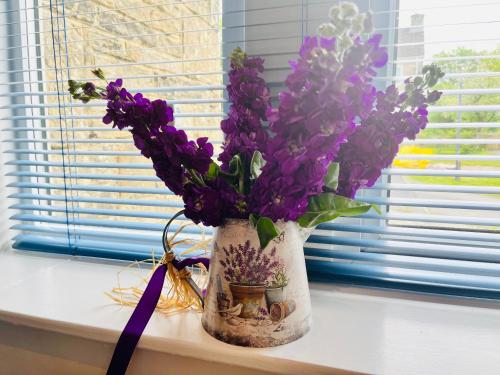 a vase of purple flowers sitting on a window sill at Grassington Cottage in Grassington