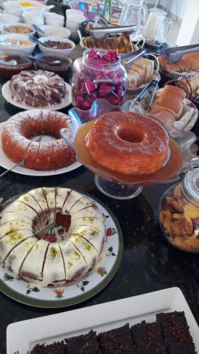 una tavola piena di diversi tipi di torte e pasticcini di Pousada Riviera Bombinhas a Bombinhas