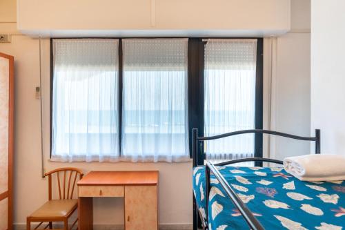 a bedroom with a bed and a table and windows at Hotel Montmartre in Rimini