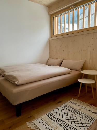 a bed in a room with a window and a rug at Apartment Waldblick in Mellau