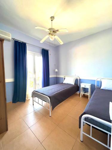 a bedroom with two beds and a ceiling fan at Grand Pension in Néa Koróni