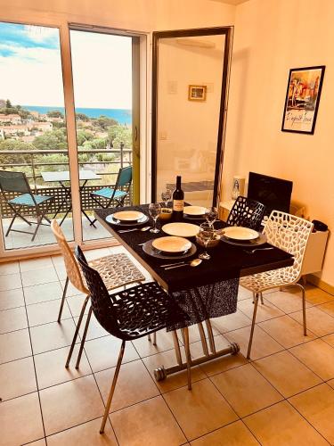 une salle à manger avec une table et des chaises et un balcon dans l'établissement Appartement Sous le Soleil vue mer, parking inclus , clim ,wifi, à Collioure