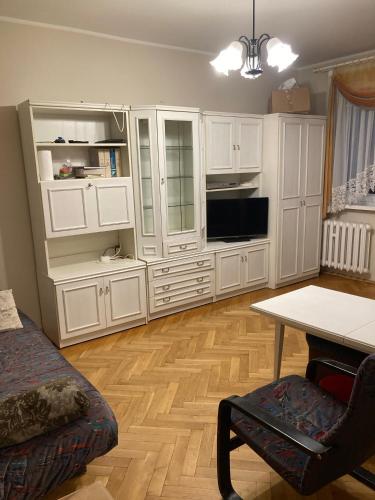 ein Wohnzimmer mit weißen Schränken und einem Tisch in der Unterkunft Apartament Roma in Danzig