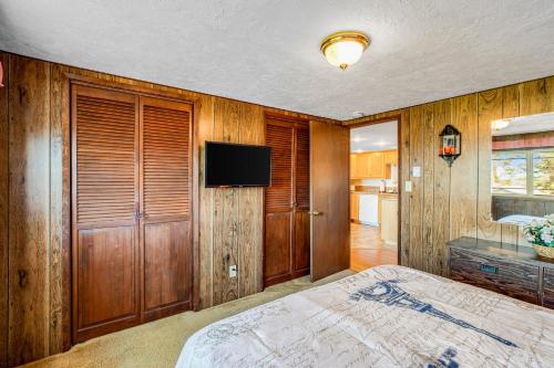 a bedroom with wooden walls and a bed with a television at All Well and Wood in Tillamook