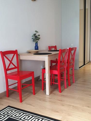 a dining room table with four red chairs at Apartament Wrzeszcz, blisko morza in Gdańsk