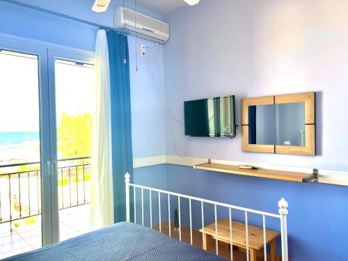 Schlafzimmer mit einem Bett, einem TV und einem Balkon in der Unterkunft Grand Apartments in Néa Koróni