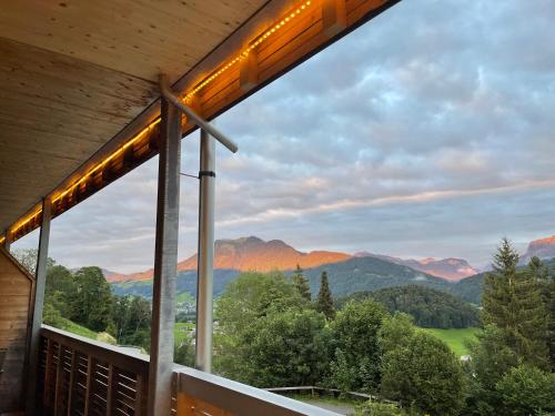a view of a mountain range from the porch of a house at Panoramahotel Sonnhalde in Schwarzenberg im Bregenzerwald