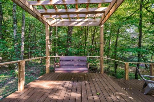a wooden porch with a swinging bench in the woods at Lazy Bear Cabin in Epworth